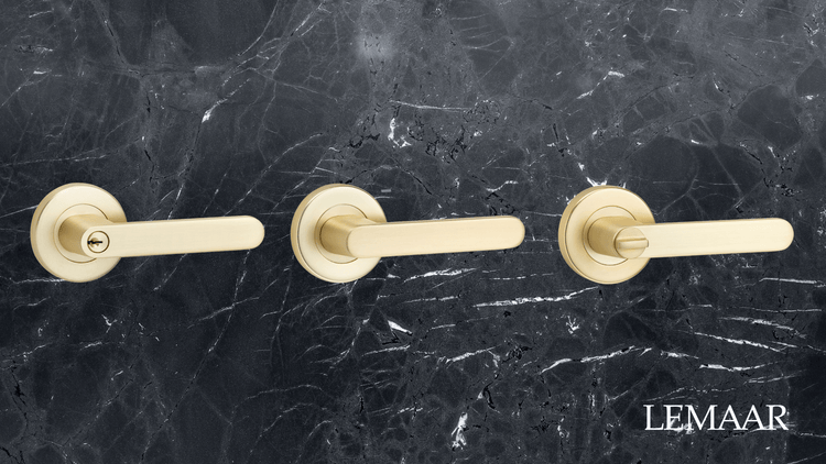 Row of brushed brass door handles on marble background.